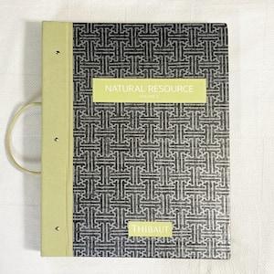 May include: A rectangular sample book with a light green spine and a dark gray cover featuring a white geometric pattern. The cover displays a light green label with the text NATURAL RESOURCE VOLUME 2 and a smaller label with the text THIBAUT.