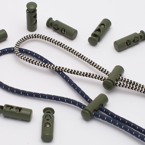 Puede incluir: Un surtido de cierres de cordón verde oliva y cordones. Los cordones son en blanco y negro, y azul marino y blanco. Los cierres de cordón son cilíndricos con tres agujeros. Los cordones están en bucle y listos para usar.