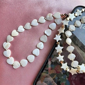 Mother of pearl phone charm chain.  Heart shaped mother of pearl bead phone charm chains for hands free phone use.  Mobile phone accessories.
Star shaped mother of pearl phone charm chain.
Seashell mobile phone charm.
Mobile phone lanyard.