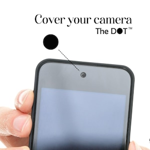 May include: A black phone with a black camera cover, with the text "Cover your camera The DOT" in a white font. The phone is held by a hand against a white background. The Creekside Craftworks logo is in the bottom right corner.