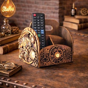 Può includere: Un porta telecomando in legno con un design steampunk. Il supporto presenta intricati dettagli di orologeria e ingranaggi nei toni dell'oro e del bronzo. Un telecomando nero è posto all'interno. Il supporto è su una superficie di legno.
