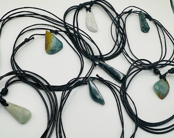 May include: Seven necklaces with different colored stone pendants on black cords. The stones are green, blue, white, and brown.