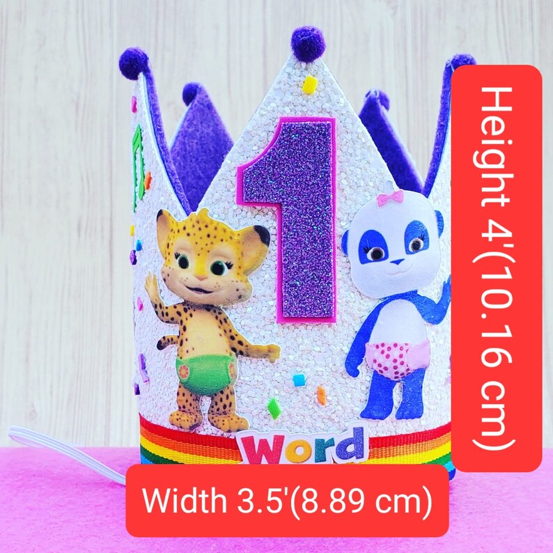 Puede incluir: Corona de cumplea&ntilde;os de color morado y blanco con un n&uacute;mero uno brillante, un personaje de guepardo y un personaje de panda, y la palabra "Word" en una cinta de arco&iacute;ris. La corona mide 10,16 cm de alto y 8,89 cm de ancho.