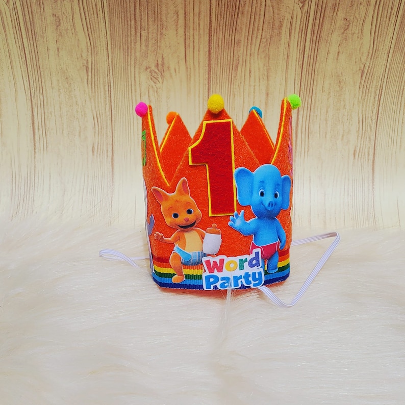 May include: Orange felt crown with a rainbow border and the words "Word Party" on the bottom. The crown features a number one, a blue elephant character, and a red kangaroo character.