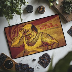 May include: A rectangular desk mat featuring a graphic illustration of a man in a yellow tank top with his hand on his forehead. The text reads, IT DON T MATTER. NONE OF THIS MATTERS. - Carl Brutananadilewski, set against a warm red and gold background.