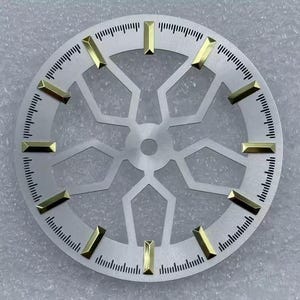Pode incluir: Um mostrador de rel&oacute;gio prateado com marcadores de hora retangulares dourados. O mostrador tem um design geom&eacute;trico no centro e uma escala de minutos ao redor do per&iacute;metro. Este mostrador &eacute; um componente para a relojoaria, com cerca de 3,5 cm de di&acirc;metro.
