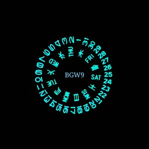 May include: A circular watch face with a black background and a glowing turquoise dial. The dial displays the days of the week, the numbers 1 through 31, and the text "BGW9".