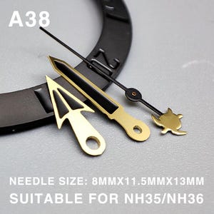 May include: A collection of watch hands in gold and black. The set includes a gold arrow-shaped hand, a gold and black rectangular hand, and a black hand with a gold turtle design. The text "A38" is visible. The text "NEEDLE SIZE: 8MMX11.5MMX13MM SUITABLE FOR NH35/NH36" is also visible.