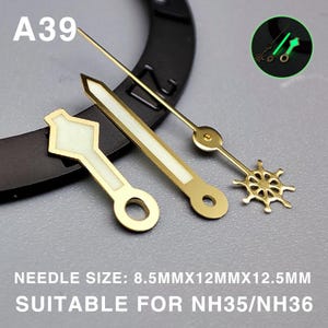 May include: Close-up of watch hands in gold and white. The hands include a diamond-shaped hour hand, a long minute hand, and a second hand shaped like a ship's wheel. The text "A39" is visible. The text "NEEDLE SIZE: 8.5MMX12MMX12.5MM SUITABLE FOR NH35/NH36" is also visible.