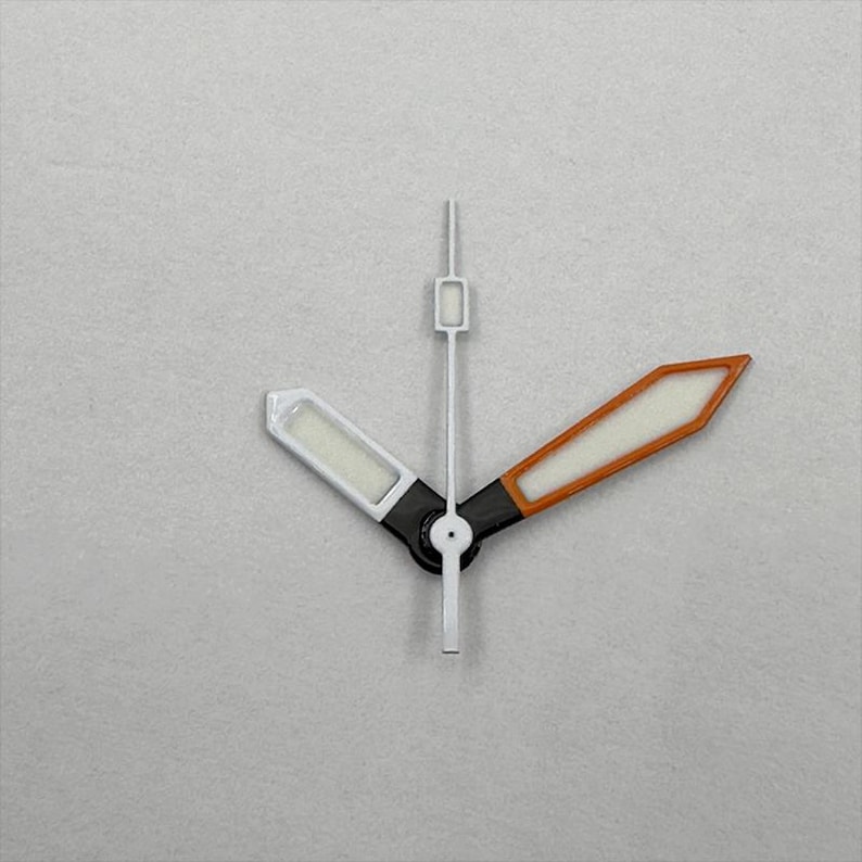 May include: Close-up of watch hands against a gray background. The hour hand is white with a rectangular tip. The minute hand is orange-brown with a white interior. The second hand is white and thin. The hands are black at the base.