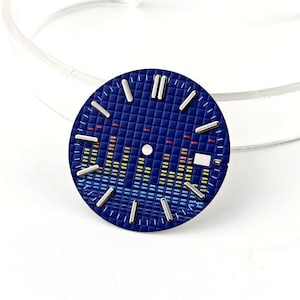 Könnte beinhalten: Blaues Zifferblatt mit strukturiertem, gitterartigem Muster. Silberfarbene Stundenmarkierungen und Zeiger sind vorhanden. Das Zifferblatt zeigt ein grafisches Equalizer-Design in Blau-, Gelb- und Rottönen.