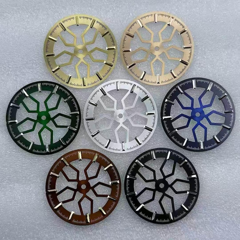 Pode incluir: Uma cole&ccedil;&atilde;o de sete componentes circulares de rel&oacute;gio em v&aacute;rias cores, incluindo dourado, verde, prateado, azul, castanho e preto. Cada componente apresenta um design geom&eacute;trico com linhas radiais e uma escala numerada na borda.