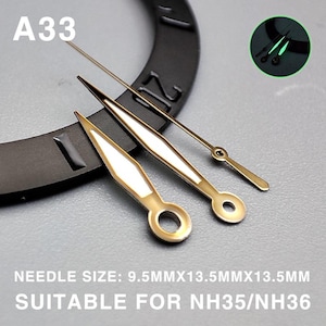 May include: Watch hands in gold and white with a luminous glow. The set includes a second hand and two other hands. The text "A33" is visible. The text "NEEDLE SIZE: 9.5MMX13.5MMX13.5MM SUITABLE FOR NH35/NH36" is also visible.
