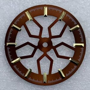 Pode incluir: Um mostrador de rel&oacute;gio circular com acabamento bronze e recortes geom&eacute;tricos. Marcadores de hora retangulares dourados s&atilde;o espa&ccedil;ados uniformemente ao redor do per&iacute;metro do mostrador. O mostrador apresenta uma faixa de minutos detalhada e um centro.