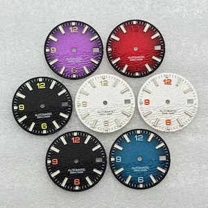 Puede incluir: Siete esferas de reloj circulares con un patrón de ondas texturizado, cada una con el texto AUTOMATIC 200m/660ft. Las esferas son de color morado, rojo, negro con números amarillos, blanco con números plateados, blanco con números naranjas, negro con números naranjas y azul.