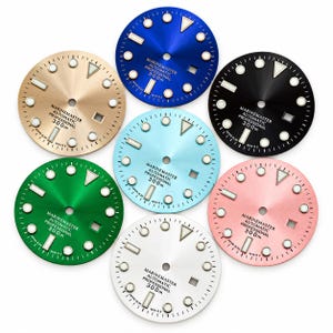 Puede incluir: Una colección de siete esferas de reloj circulares en azul, negro, dorado, verde, azul claro, rosa y blanco. Cada esfera presenta marcadores de hora luminosos, un orificio central, una ventana de fecha y el texto MARINEMASTER AUTOMATIC PROFESSIONAL 300m.