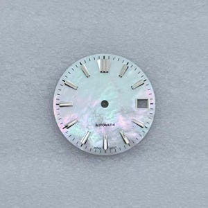 May include: A watch face with a pearlescent, iridescent finish. The face features silver-toned hour markers and hands, with the word "AUTOMATIC" printed in black. The bottom of the face reads "JAPAN MOVT".