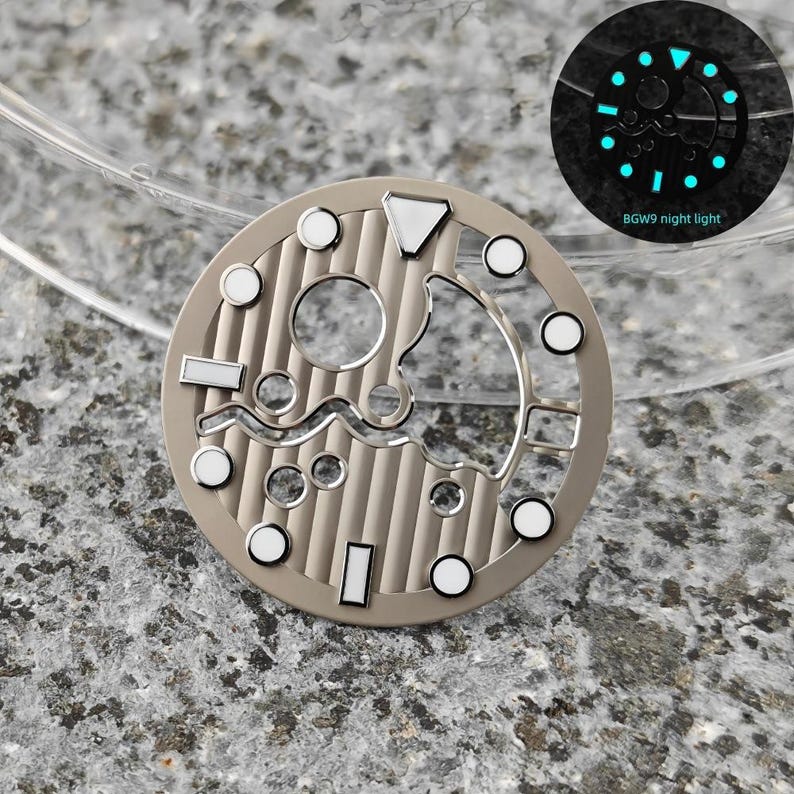 May include: A watch dial with a beige finish, featuring a series of circular and rectangular markers with white accents. The dial has a unique open design with a textured background. A smaller inset shows the dial glowing with a blue night light. The text "BGW9 night light" is visible.