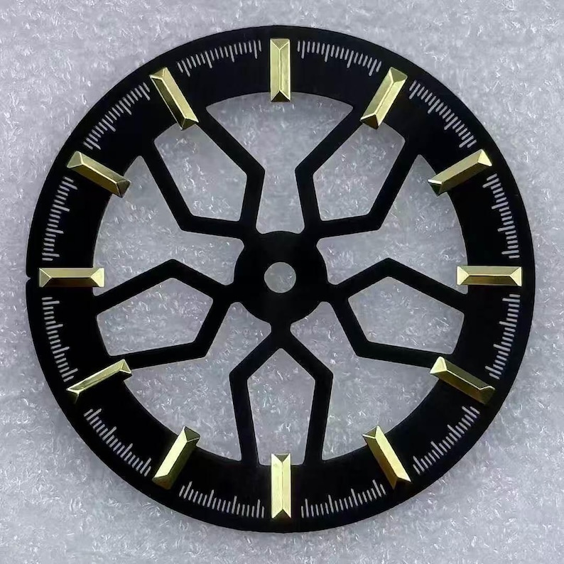 Pode incluir: Um mostrador de rel&oacute;gio preto com marcadores de hora dourados e um design geom&eacute;trico. O mostrador &eacute; circular com pequenas linhas na borda para as indica&ccedil;&otilde;es dos minutos. Os marcadores dourados s&atilde;o retangulares e espa&ccedil;ados. O di&acirc;metro &eacute; de cerca de 3,5 cm.