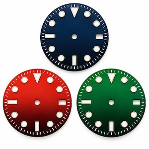 May include: Three circular watch dials in blue, red, and green, each featuring a central hole, white minute markers, and raised hour indices with white luminous centres. Each dial includes a triangular marker at twelve and a date window at three.