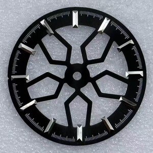 Pode incluir: Um mostrador de rel&oacute;gio preto com um design geom&eacute;trico. O mostrador apresenta marcadores de hora prateados e uma s&eacute;rie de linhas ao redor da borda externa. O centro do mostrador tem uma abertura circular.