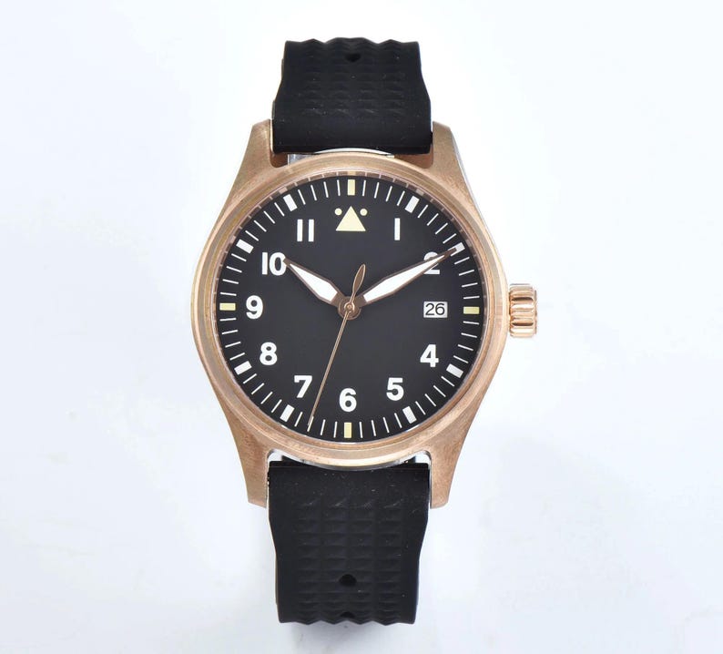 May include: A bronze-colored wristwatch with a black face and white numerals. The watch has a black rubber strap and a date display at the 3 o'clock position. The watch case is approximately 40mm in diameter.