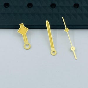 K&ouml;nnte beinhalten: Ein Set aus drei Keramikbechern mit gesprenkelter, matter Oberfl&auml;che. Die Becher sind in Creme-, Hellgrau- und Dunkelgraut&ouml;nen gehalten. Jeder Becher hat ein schlichtes, minimalistisches Design und einen abgerundeten Henkel.