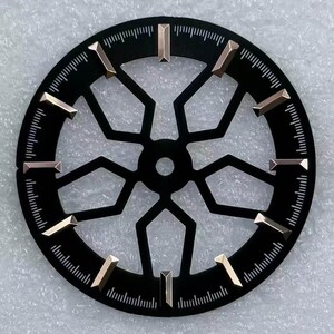 Pode incluir: Um mostrador de rel&oacute;gio preto com um design geom&eacute;trico e marcadores de hora dourados. O mostrador tem formato circular com marca&ccedil;&otilde;es de minutos na borda. Os marcadores de hora s&atilde;o retangulares e angulados.