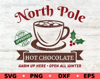 May include: A brown graphic with the words "North Pole" in a decorative font above a cup of hot chocolate with marshmallows. Below the cup is a banner that reads "HOT CHOCOLATE". A green stamp says "Santa Approved Claus".