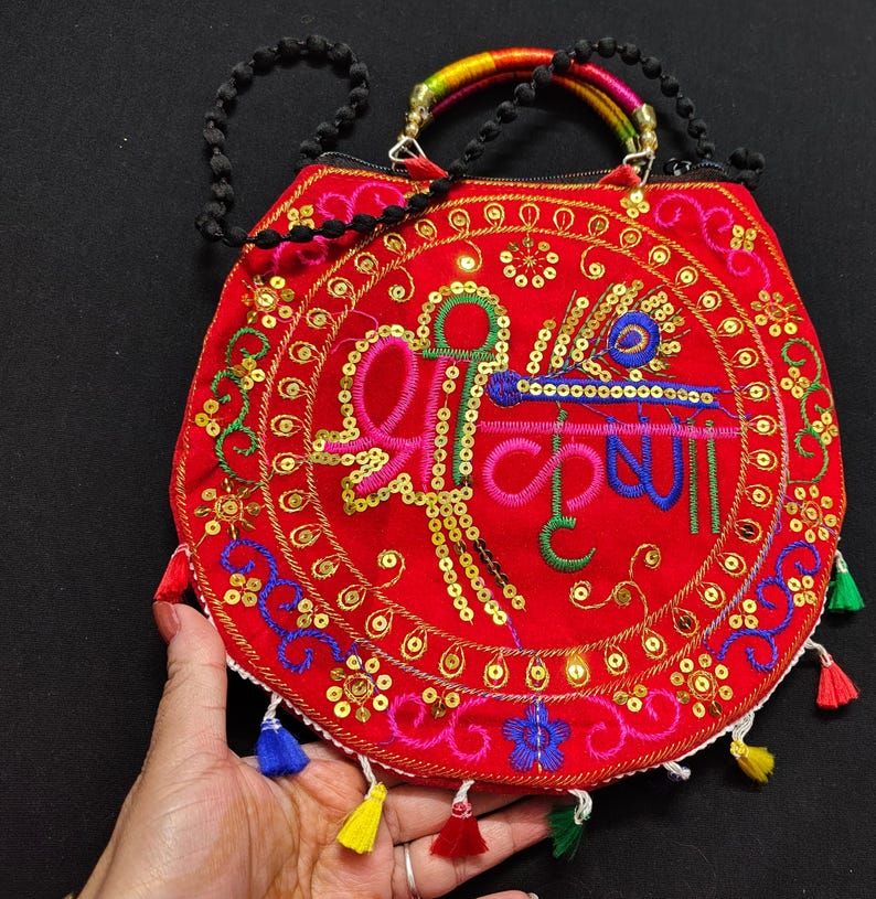 Puede incluir: Bolso de mano rojo bordado con lentejuelas doradas y borlas coloridas. El bolso presenta un dise&ntilde;o central con texto en verde y azul, un asa de cuentas negras y un asa superior de arco&iacute;ris.