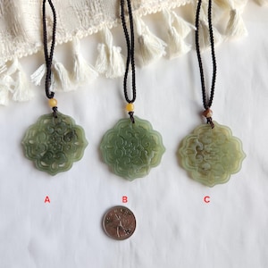 May include: Three jade pendants with intricate floral designs, each suspended from a black cord necklace. The pendants are in shades of green and cream, with a coin for size comparison. The pendants are labeled A, B, and C.