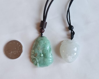 May include: Two jade pendants on black cords. The pendant on the left is green and carved with a floral design. The pendant on the right is white and smooth. A US quarter is included for size reference.
