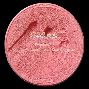 May include: A circular container of pink textured modeling paste with a thick, grainy consistency. The surface features visible tool marks and indentations. The text Ezgi Sertcetin Premium 3D Sculpture Painting Paste Modeling Paste is printed in white.