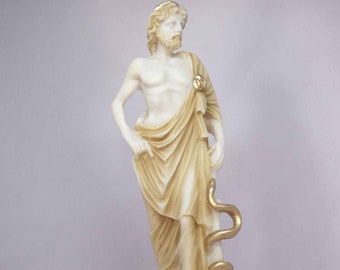 May include: White marble statue of Asclepius, the Greek god of medicine and healing, holding a snake. The statue is painted with gold accents and stands on a rectangular base.