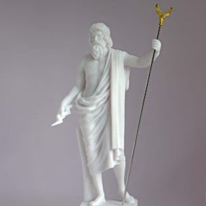May include: White marble statue of Zeus, the Greek god of the sky and thunder, holding a lightning bolt in his left hand and a scepter with an eagle on top in his right hand. The statue is standing on a base with the word "ZEUS" inscribed on it.