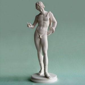 Puede incluir: Escultura blanca de una figura masculina desnuda, de pie sobre una base redonda. La figura está en una pose relajada, con un brazo sobre un hombro y el otro extendido. La escultura tiene rasgos faciales detallados y lleva botas.