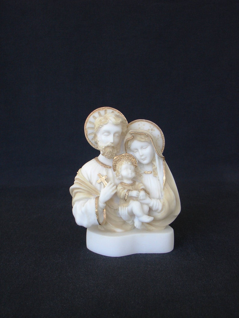 Peut inclure: Statuette en porcelaine blanche de la Sainte Famille. Les personnages sont repr&eacute;sent&eacute;s dans une pose traditionnelle avec Marie tenant l'enfant J&eacute;sus et Joseph debout &agrave; c&ocirc;t&eacute; d'eux. La statuette est d&eacute;cor&eacute;e d'accents dor&eacute;s.
