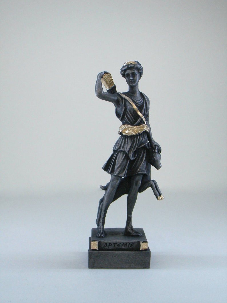 May include: A black and gold statue of Artemis, the Greek goddess of the hunt, holding a bow and arrow. She is standing on a base with the word "ARTEMIS" inscribed on it.