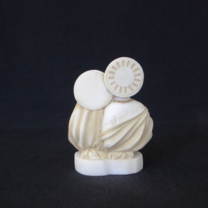 Peut inclure: Sculpture en c&eacute;ramique blanche de deux personnages, l'un avec une aur&eacute;ole ronde, debout sur une base blanche. Les personnages sont v&ecirc;tus de robes flottantes.