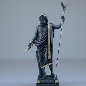 May include: Black and gold statue of Zeus, the Greek god of the sky and thunder, holding a scepter with an eagle on top. The statue is standing on a black base with the word "ZEUS" inscribed in gold letters.