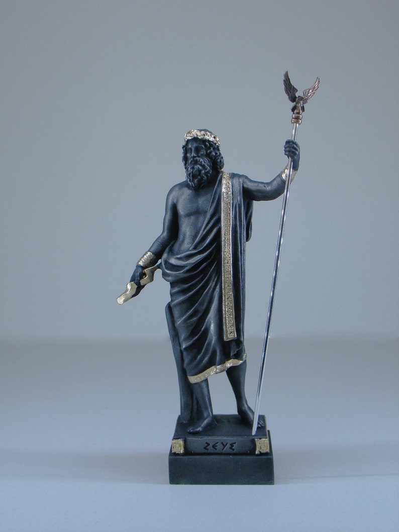 May include: Black and gold statue of Zeus, the Greek god of the sky and thunder, holding a scepter with an eagle on top. The statue is standing on a black base with the word "ZEUS" inscribed in gold letters.