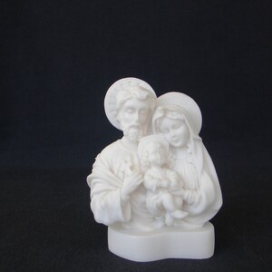 Peut inclure: Sculpture en alb&acirc;tre blanc de la Sainte Famille. La sculpture repr&eacute;sente Marie, Joseph et l'enfant J&eacute;sus. Marie tient J&eacute;sus dans ses bras et Joseph se tient derri&egrave;re eux, la main sur l'&eacute;paule de Marie.