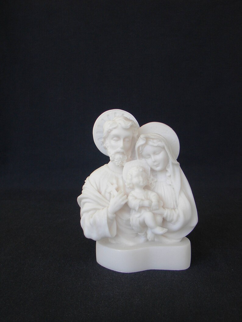 Peut inclure: Sculpture en alb&acirc;tre blanc de la Sainte Famille. La sculpture repr&eacute;sente Marie, Joseph et l'enfant J&eacute;sus. Marie tient J&eacute;sus dans ses bras et Joseph se tient derri&egrave;re eux, la main sur l'&eacute;paule de Marie.