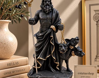 May include: A dark gray statue of Hades featuring a bearded figure in a draped robe, holding a gold-toned bident and a chain connected to a three-headed dog. The base is inscribed with the name HADES in capital letters.