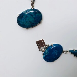 May include: A silver chain necklace with blue oval and triangular shaped stones. The stones are set in silver.