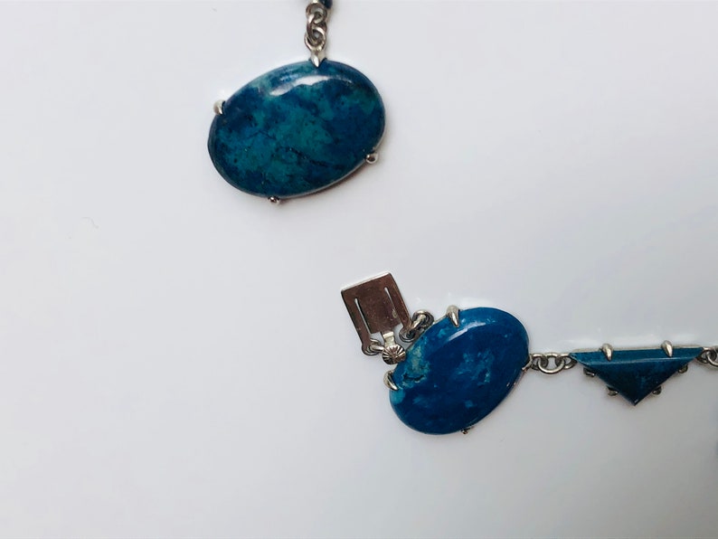 May include: A silver chain necklace with blue oval and triangular shaped stones. The stones are set in silver.