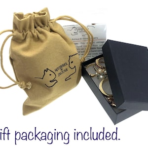 May include: A tan drawstring bag with a Squirrel Jaguar logo next to a black jewelry box with the lid open. The box contains rings and other jewelry. The text "Gift packaging included" is at the bottom.
