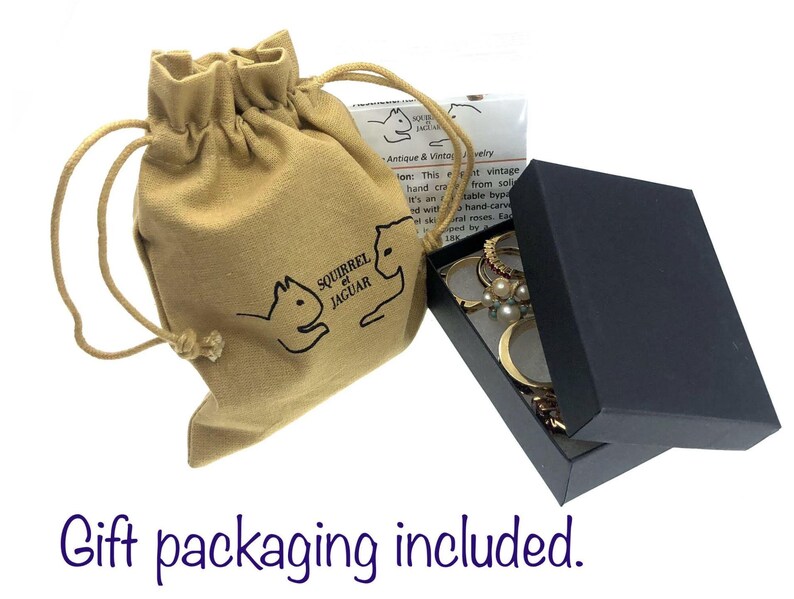 May include: A tan drawstring bag with a Squirrel Jaguar logo next to a black jewelry box with the lid open. The box contains rings and other jewelry. The text "Gift packaging included" is at the bottom.