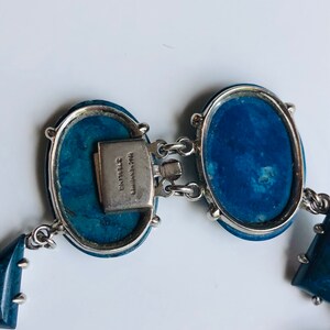 May include: A blue and silver bracelet with oval-shaped stones and a clasp that reads "Wm. Spraragen Sterling".