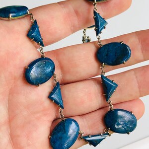 May include: A silver chain necklace with oval and triangular blue gemstone accents.